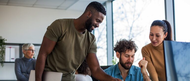 colleagues collaborating on a monitor, smiling and brainstorming