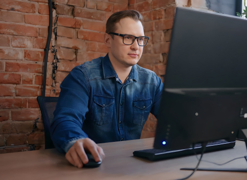 man working at a laptop in a modrn office setting