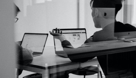 modern office setting, with two colleagues brainstorming with their laptops