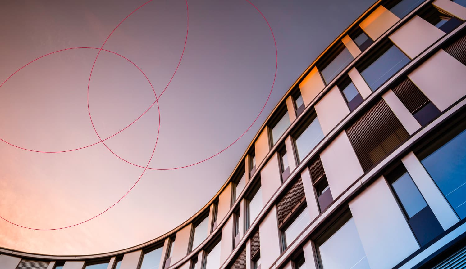 Modern curved office building with Ergo logo rings against sunset sky